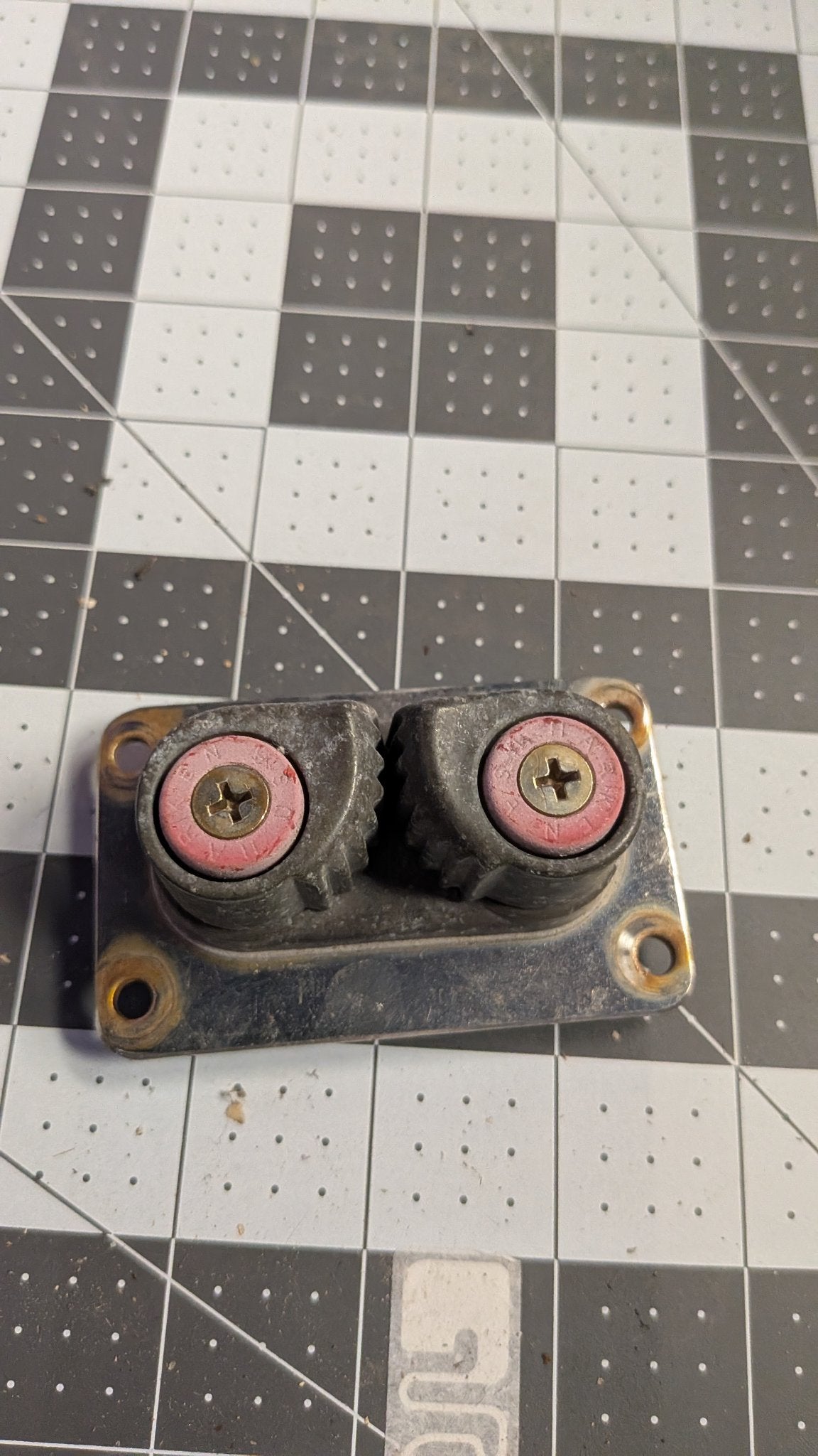 Top view of Harken double Cam-Matic cleats with red caps on 1-inch grid