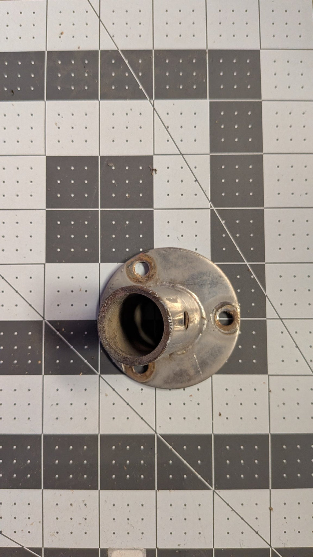 Top view of angled stanchion base showing tube socket and mounting holes on 1-inch grid
