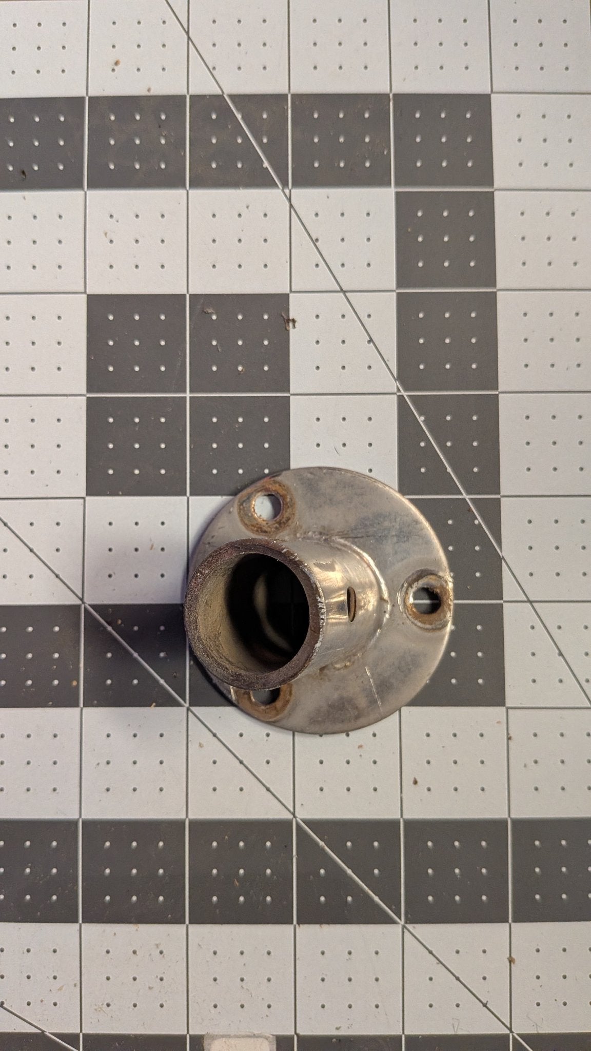 Top view of angled stanchion base showing tube socket and mounting holes on 1-inch grid
