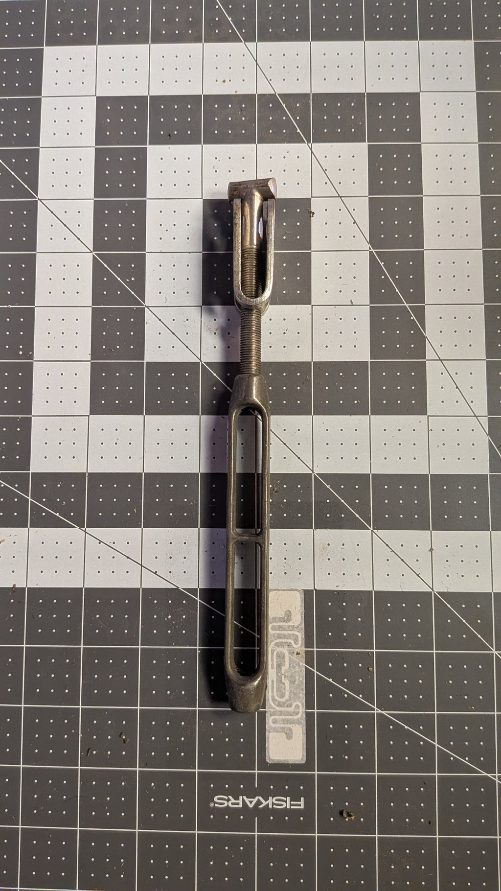 Stainless open-body turnbuckle with toggle jaw front view on 1-inch grid