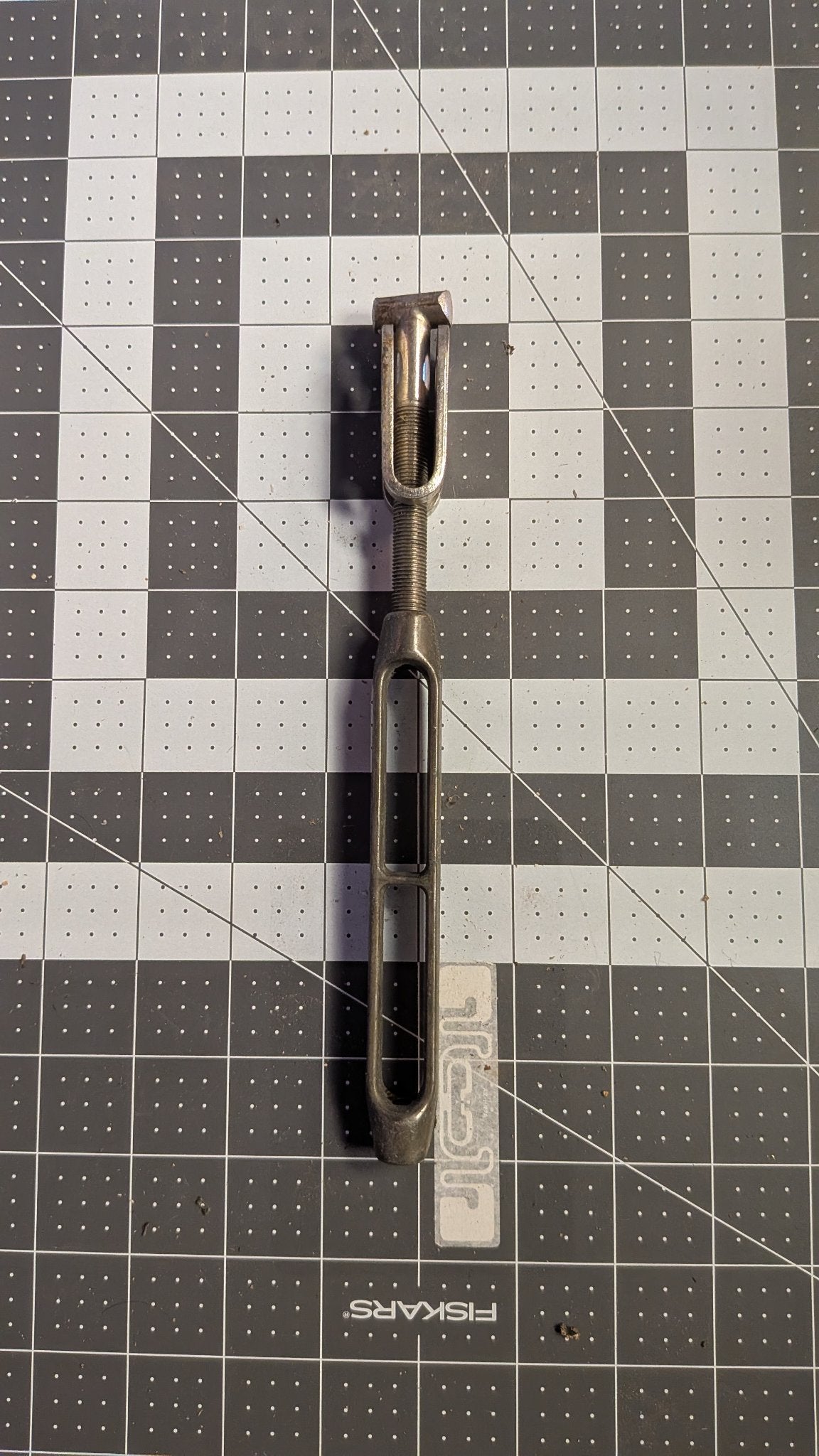 Stainless open-body turnbuckle with toggle jaw front view on 1-inch grid