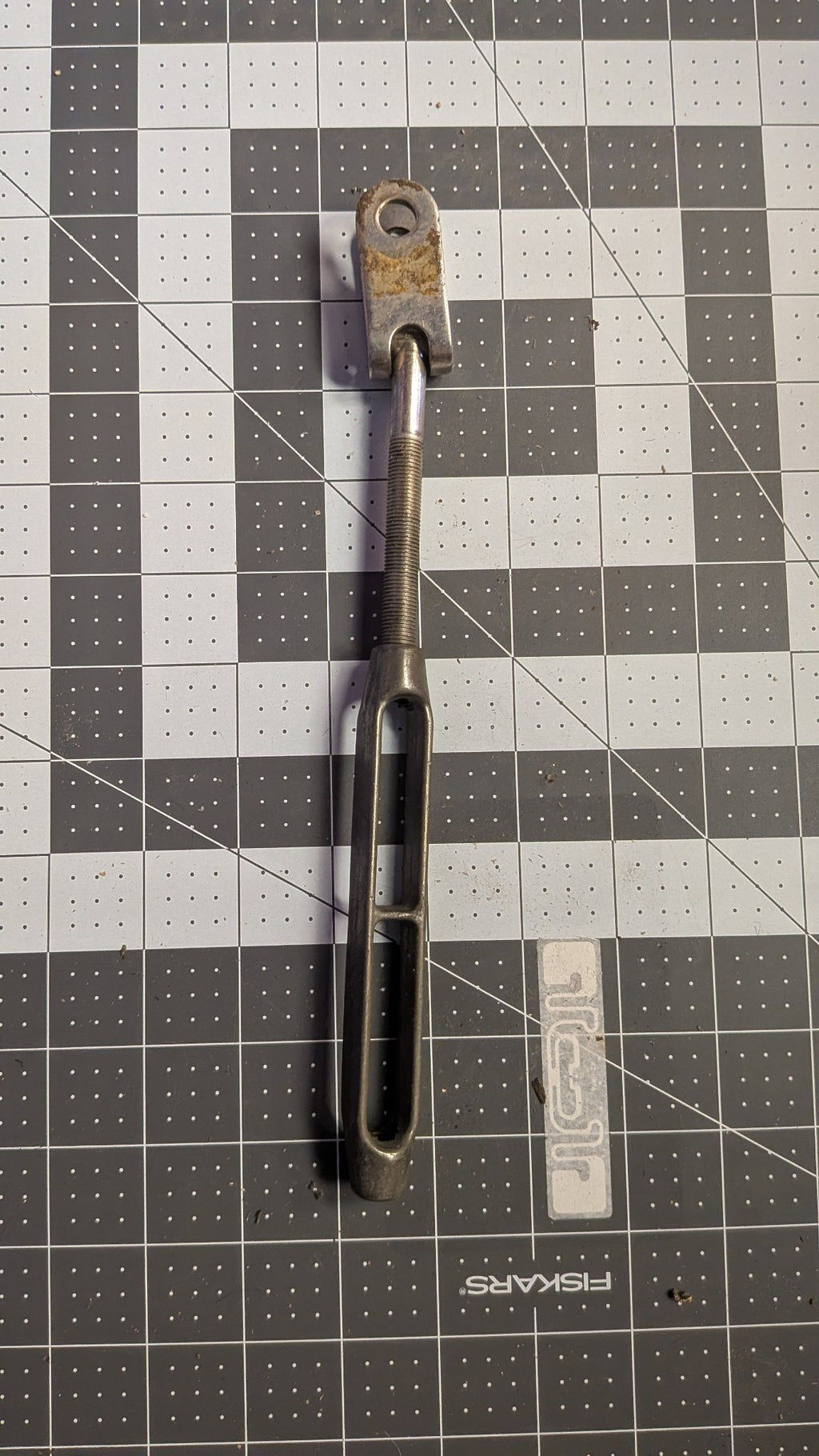 Reverse view of turnbuckle showing threaded stud on 1-inch grid