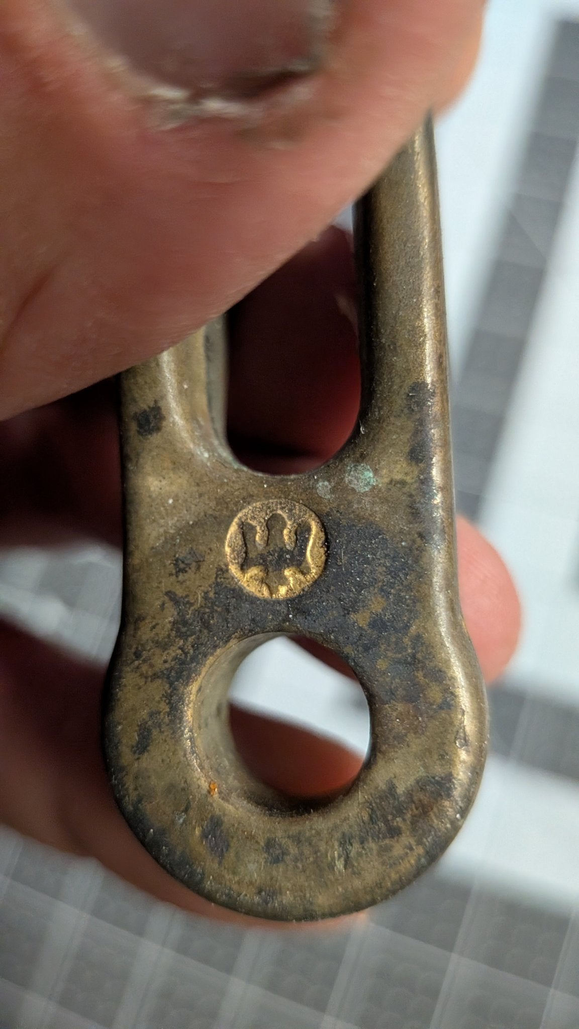 Close-up of Merriman crown maker's mark on bronze toggle