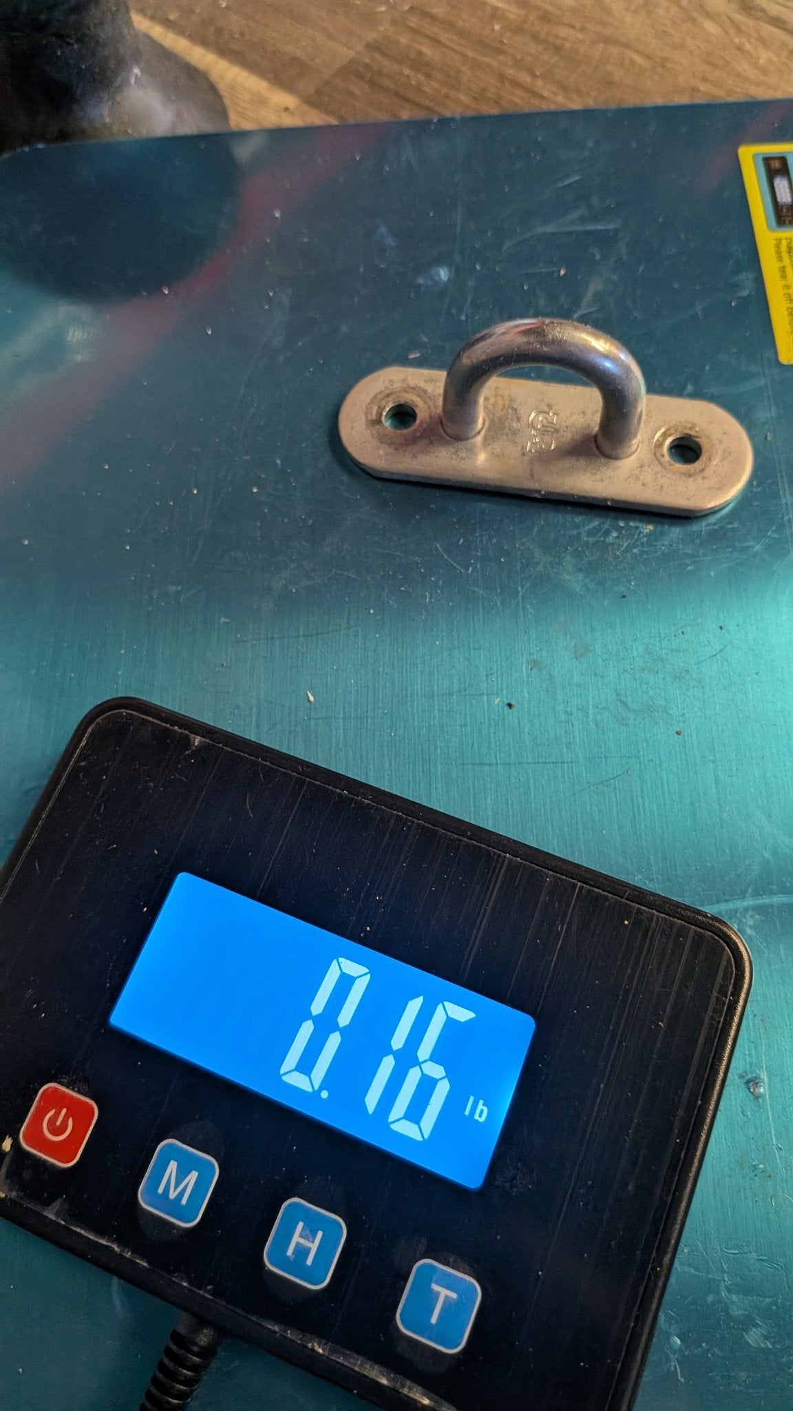 Stainless pad eye on scale showing 0.16 lb