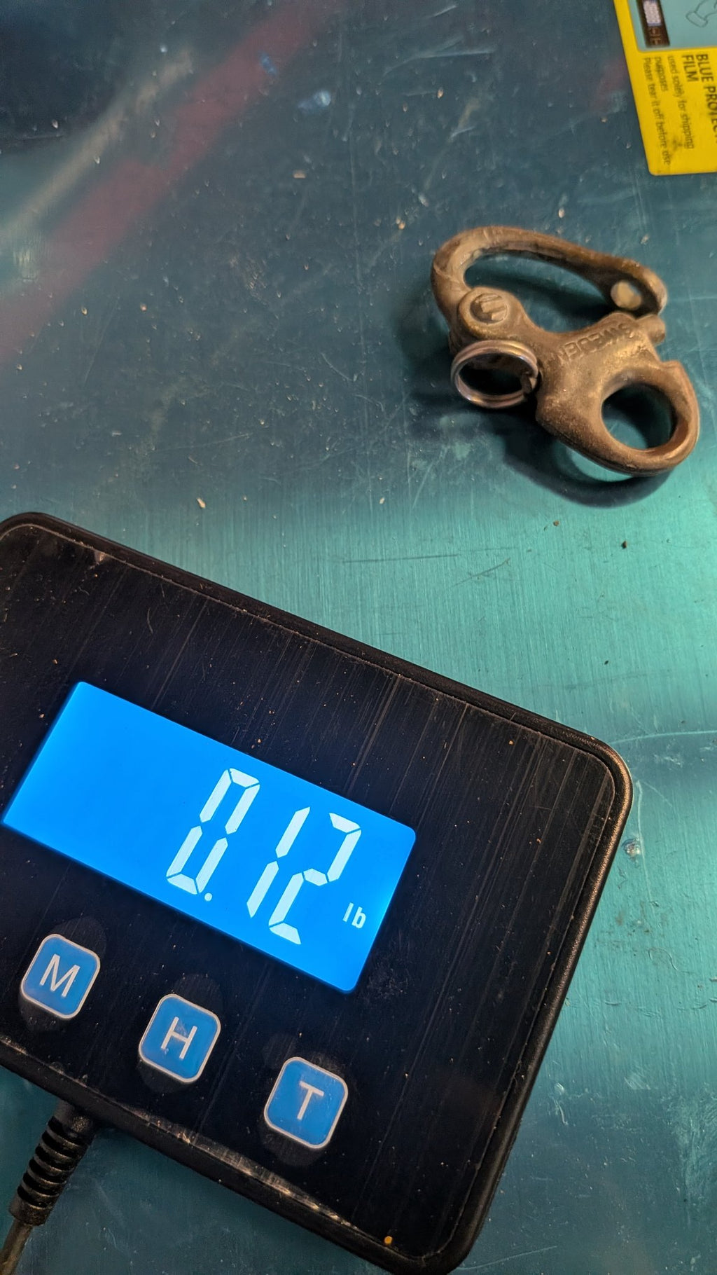 Bronze snap shackle on scale showing 0.12 lb