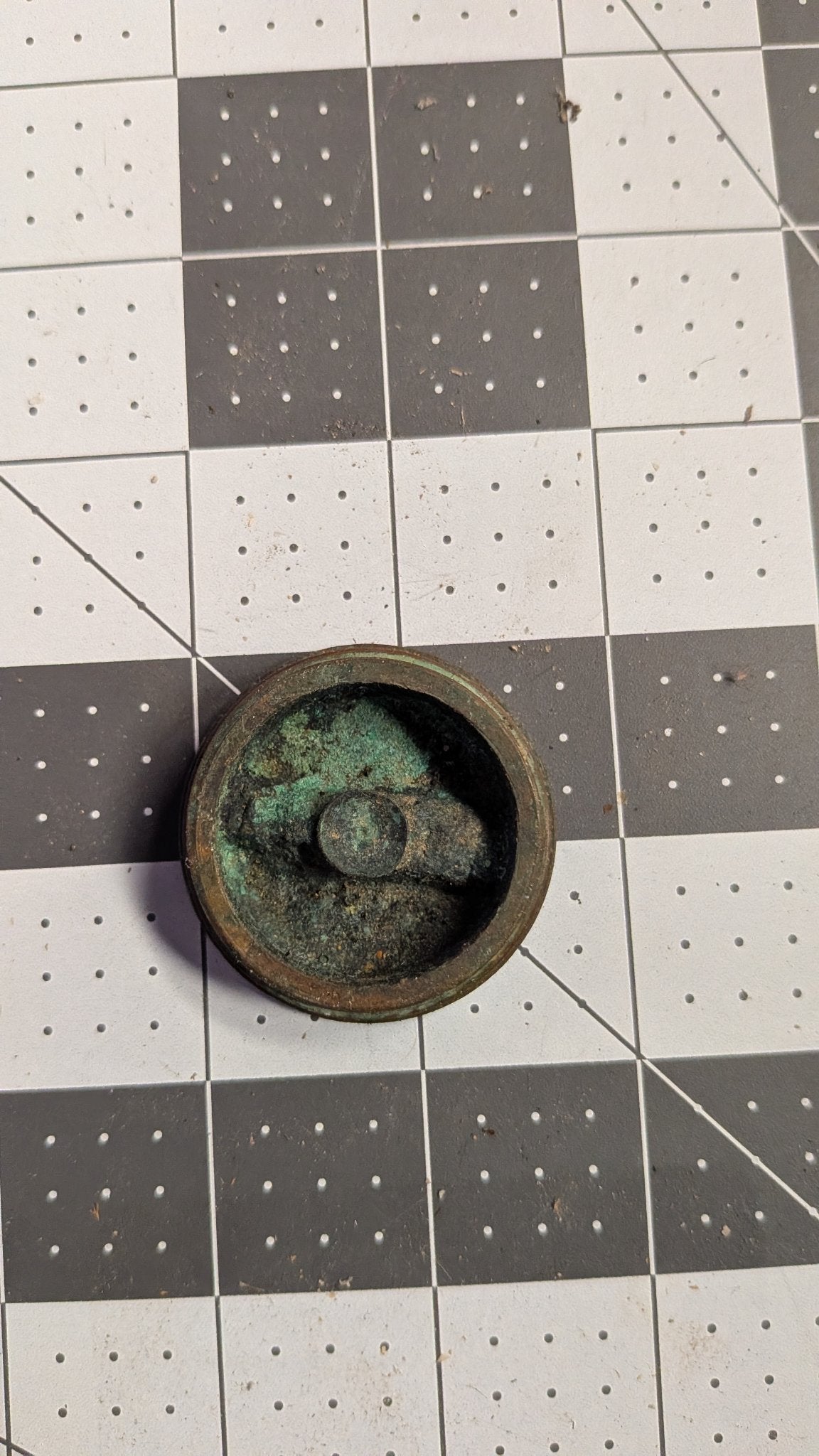 Underside of drain plug showing green patina on 1-inch grid