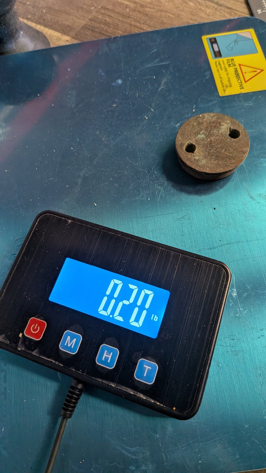 Bronze drain plug on scale showing 0.20 lb