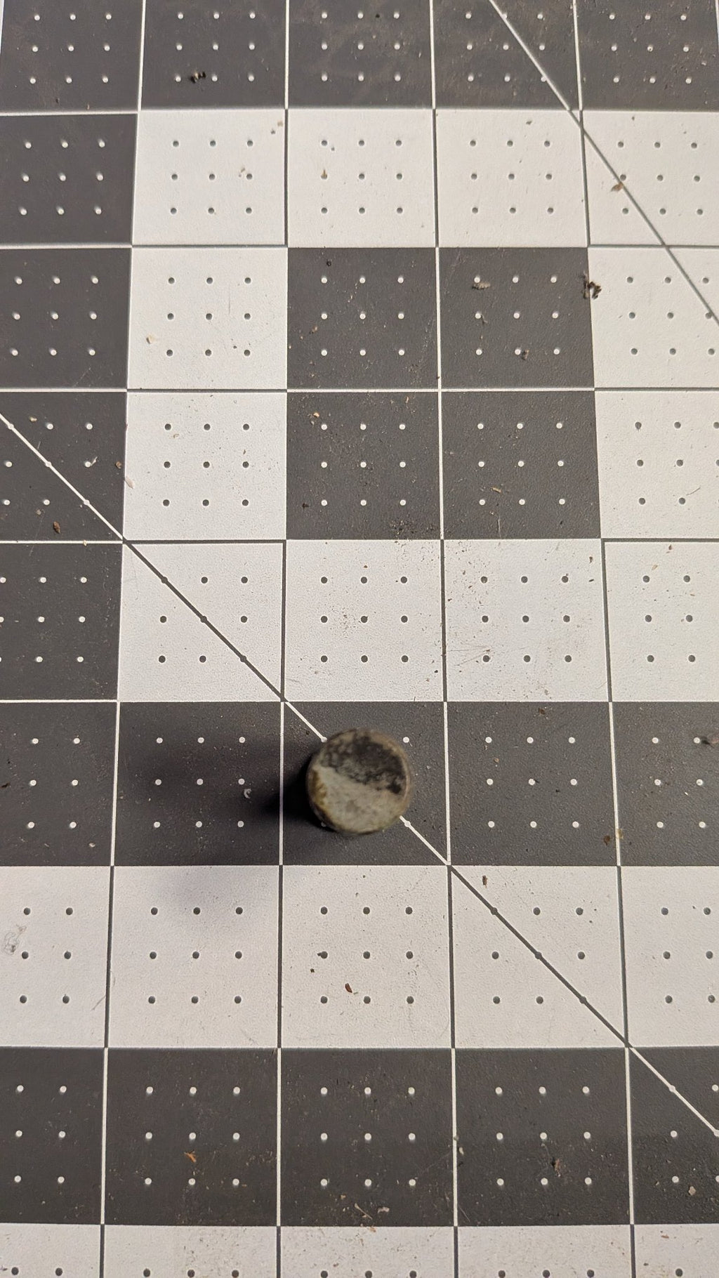 End view of bronze pivot pin on 1-inch grid