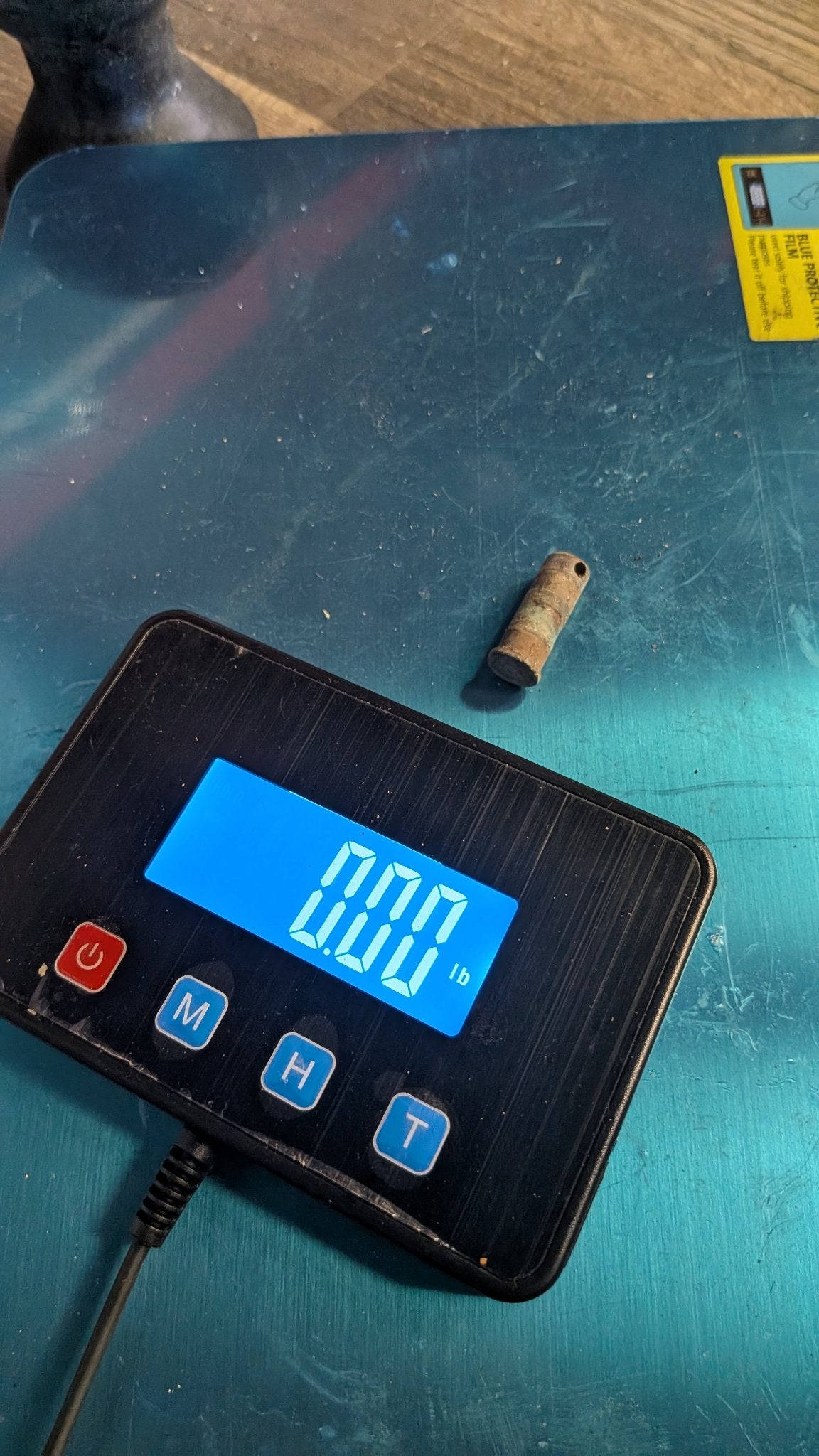 Bronze pivot pin on scale showing 0.00 lb