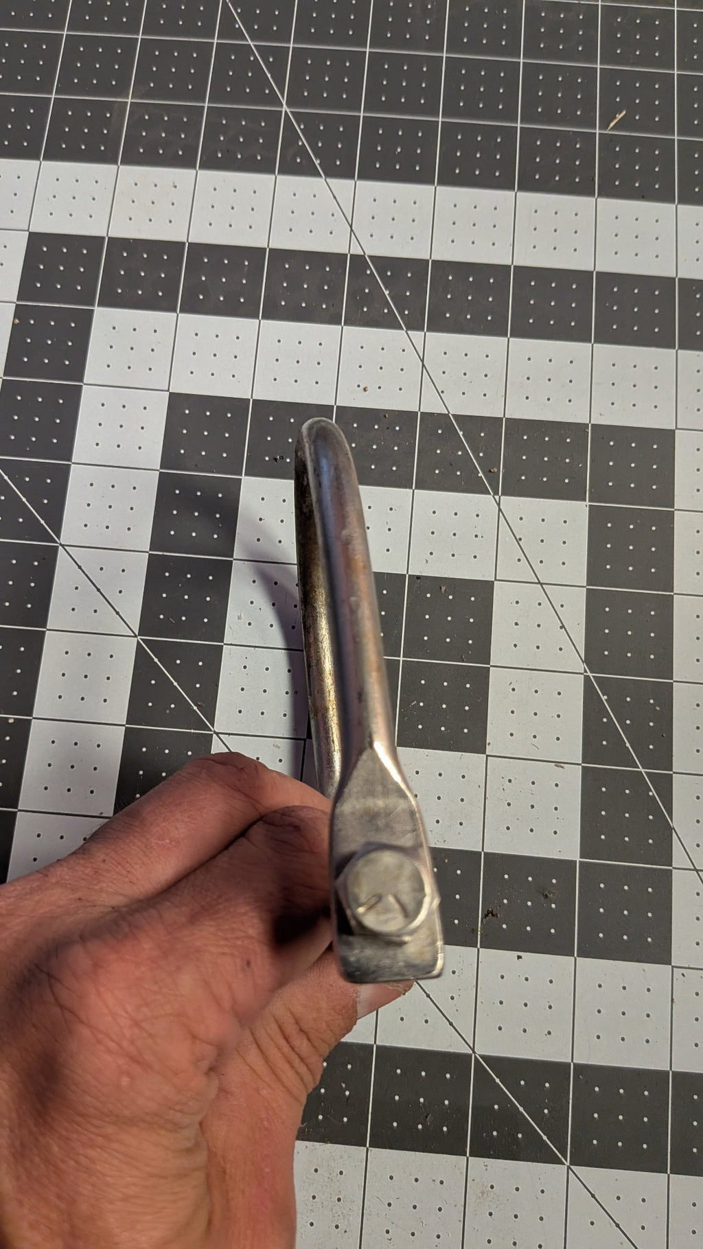 Edge view of U-bolt held in hand on 1-inch grid