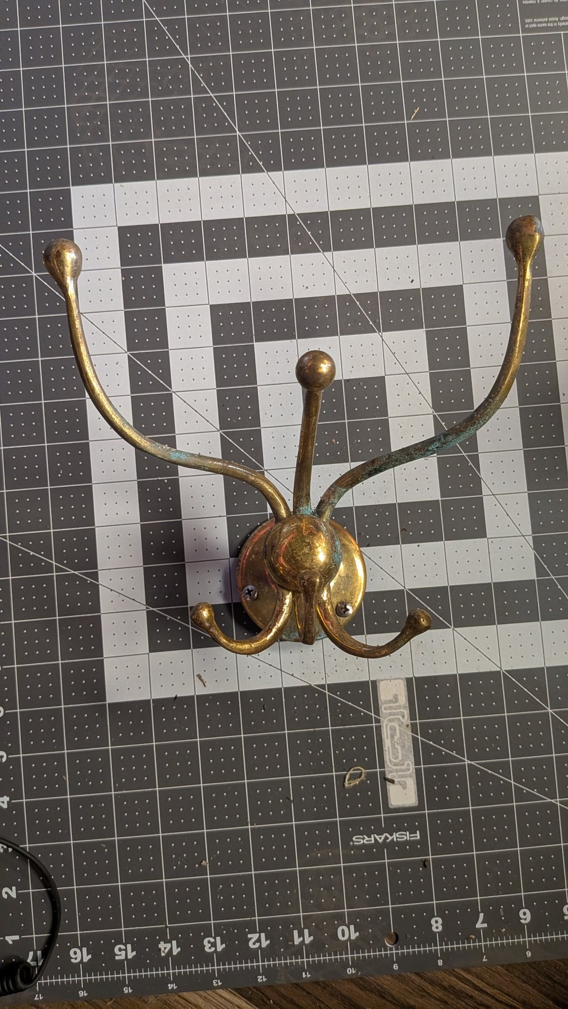 Brass 4-arm swivel coat hook front view on 1-inch grid