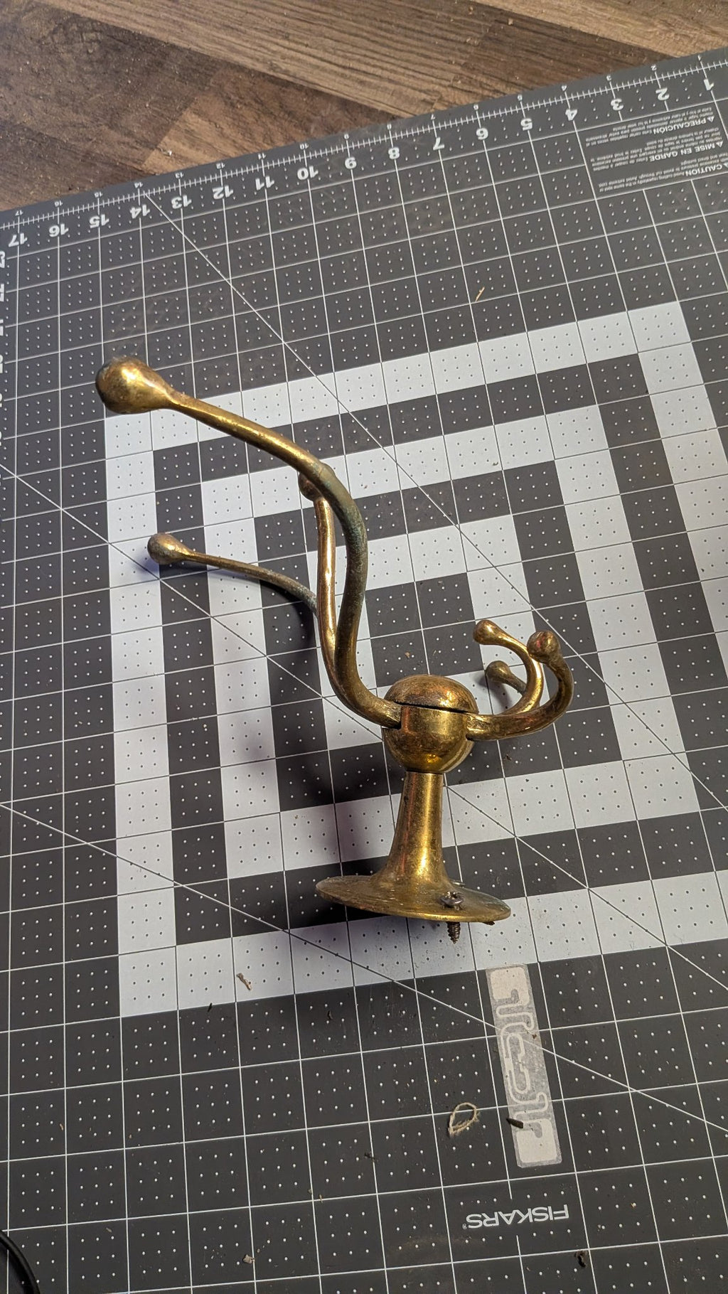 Angled view of brass coat hook on 1-inch grid