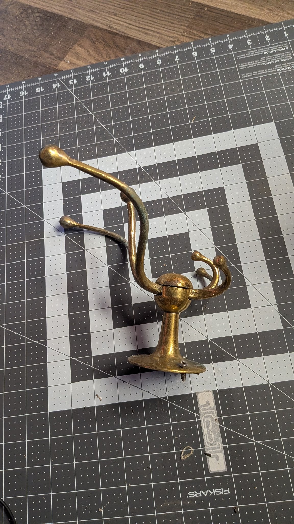Angled view of brass coat hook on 1-inch grid