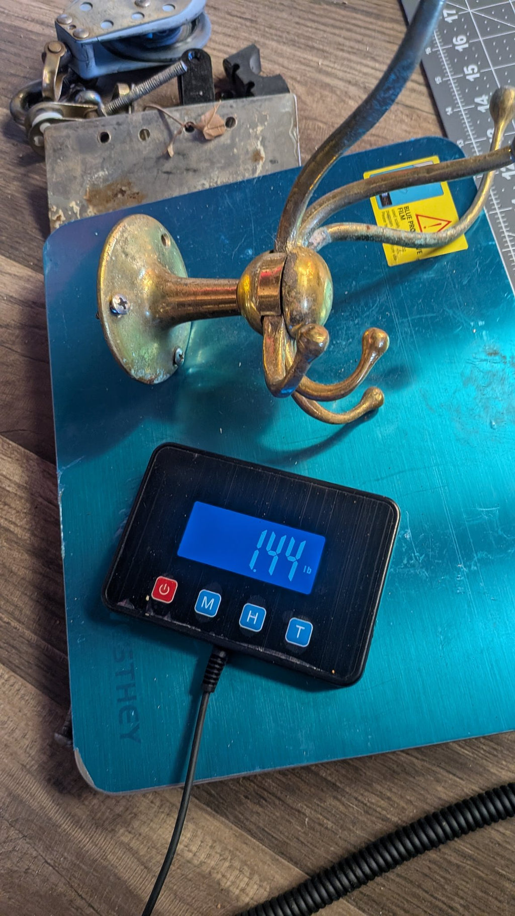 Brass coat hook on scale showing 1.44 lb