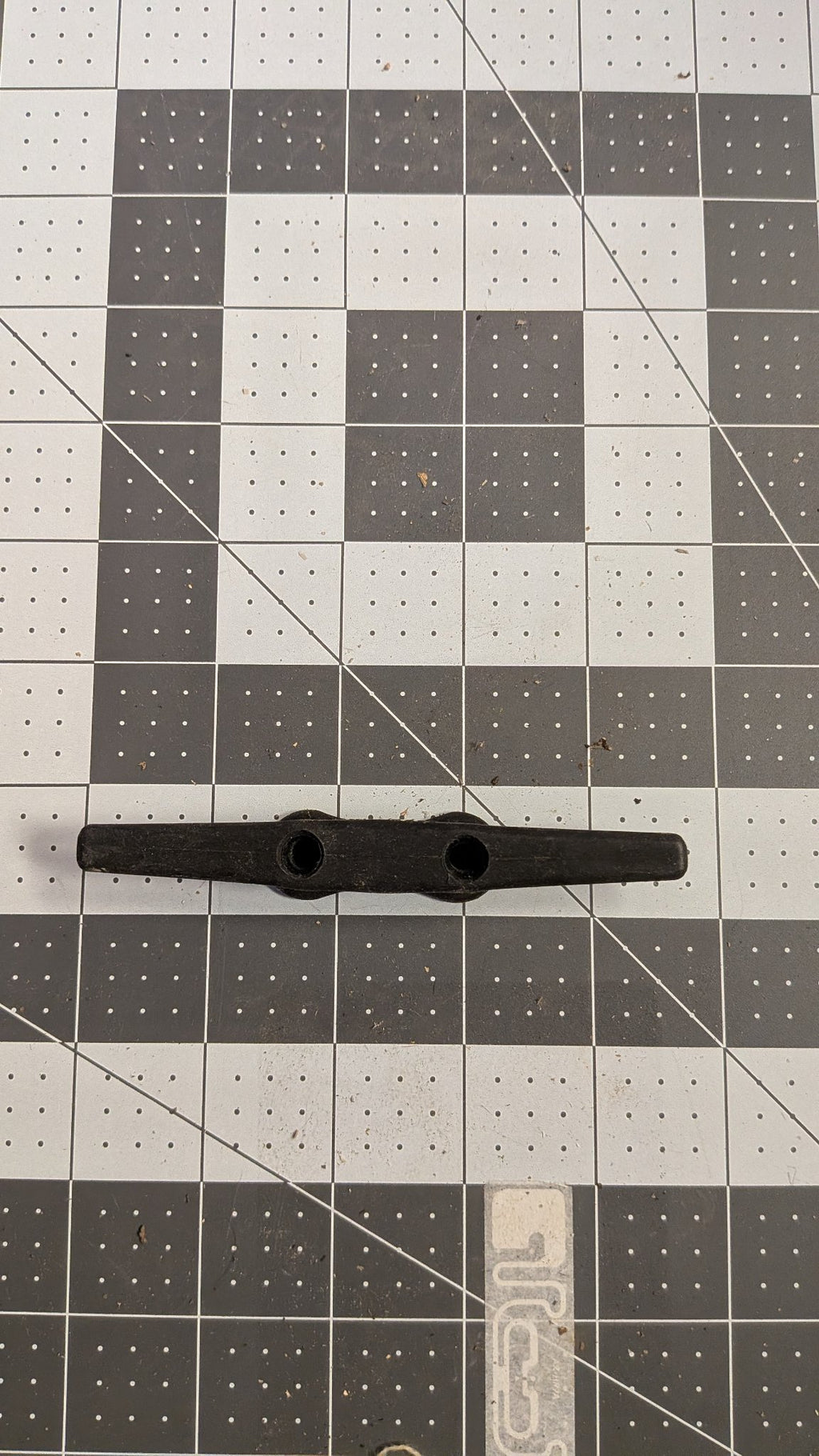 Top view of black nylon dock cleat on 1-inch grid