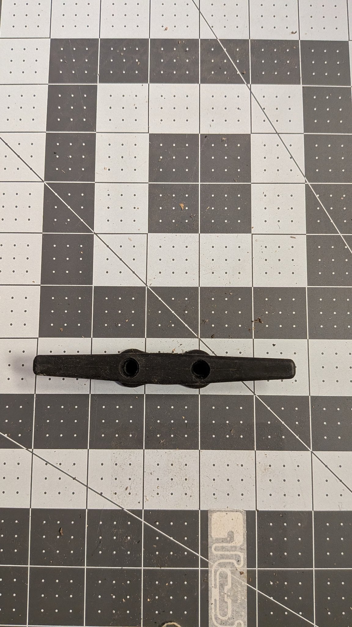 Top view of black nylon dock cleat on 1-inch grid